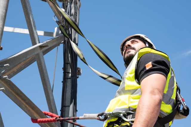 Orange technician checking a mobile antenna
