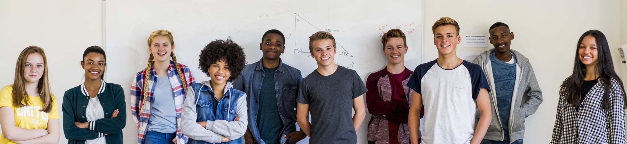 Group of students standing in front of a dry erase board smiling