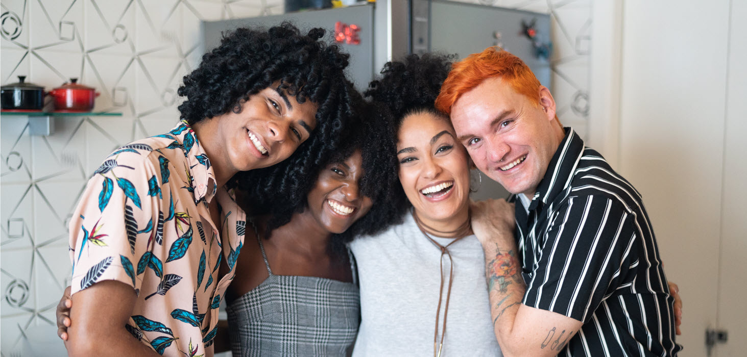 A group of four people standing together and smiling towards the camera.