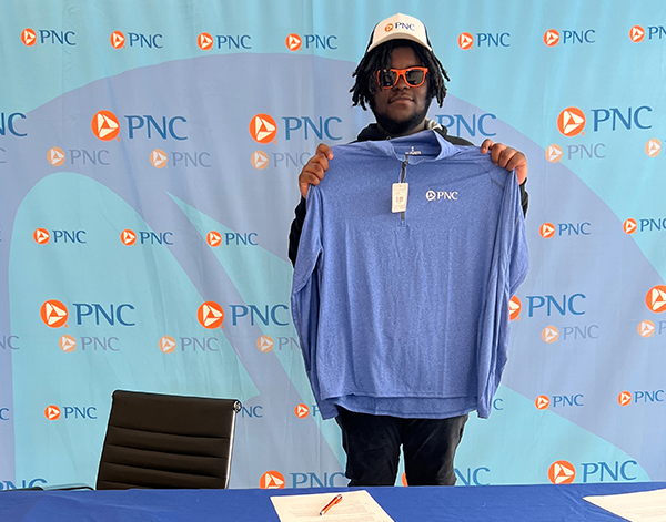 A new PartnerUp hire displays their PNC shirt on signing day