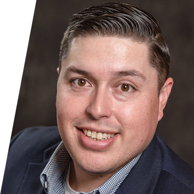 smiling man wearing a suit jacket with a brown background