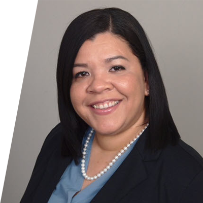 Headshot of woman with gray background, smiling with a suit jacket