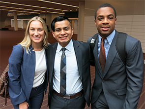 Three collegiate students stop to smile for picture