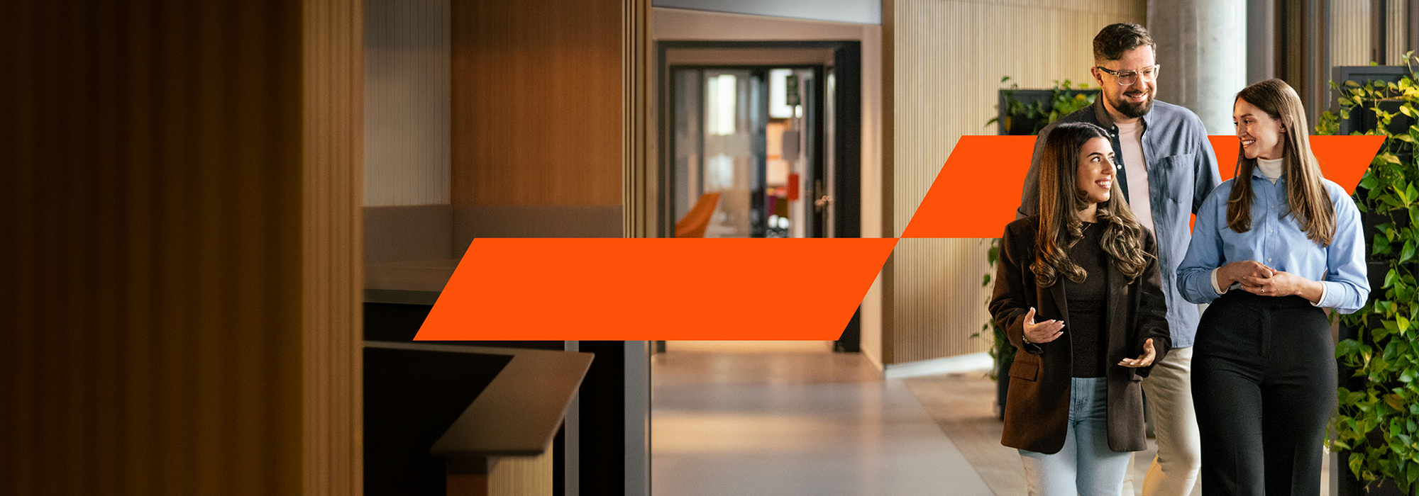 Drei Personen laufen gemeinsam durch das Büro und unterhalten sich