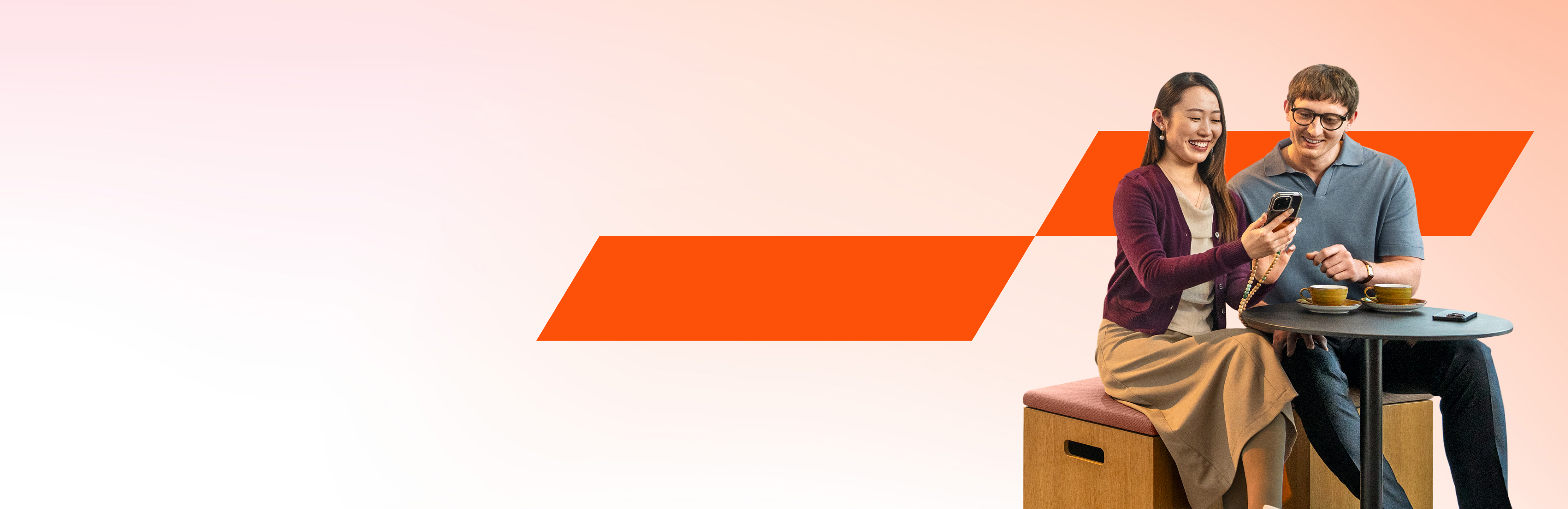 PwC Kollegen sitzen gemeinsam und schauen auf ein Smartphone