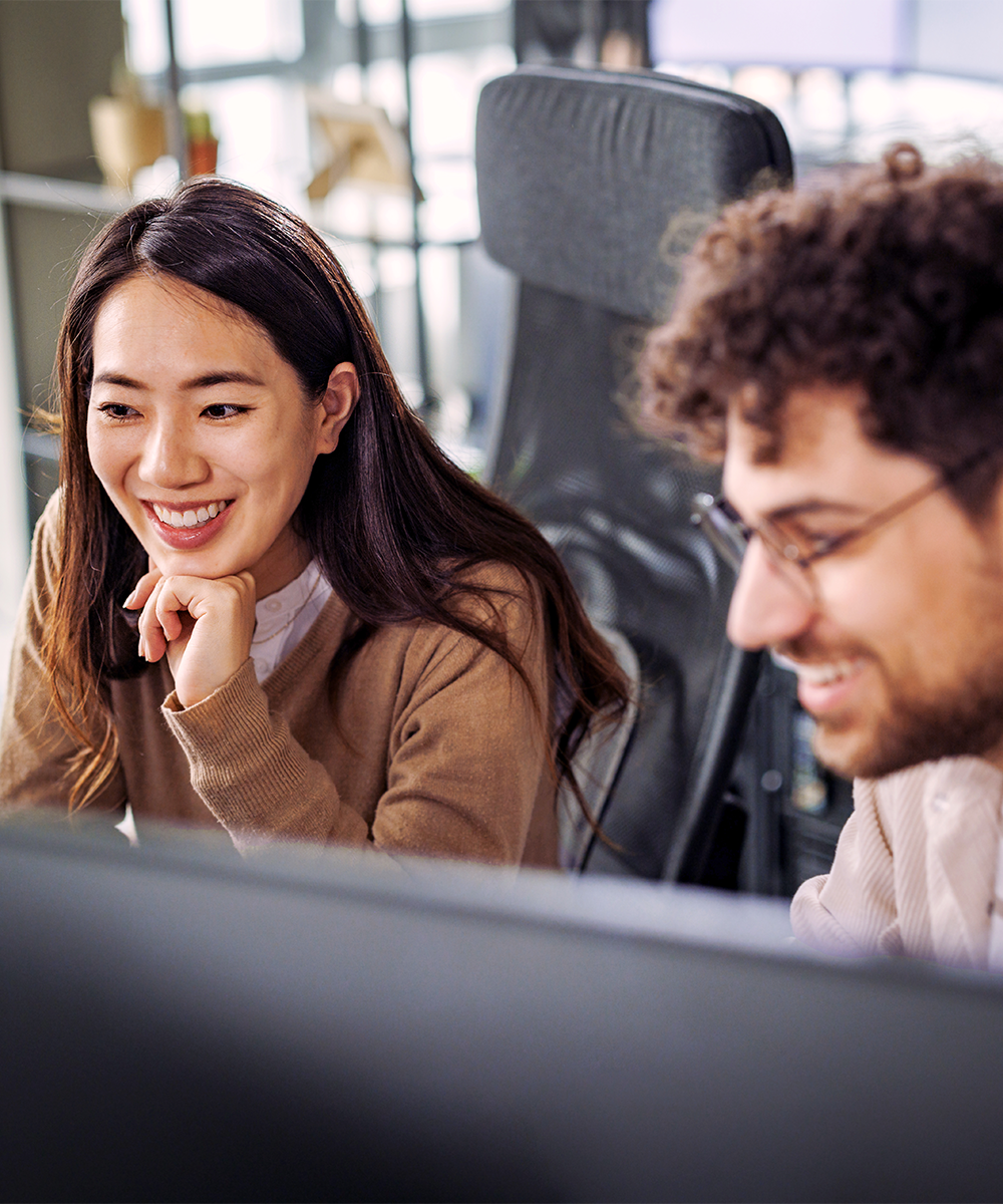 Zwei Kollegen sitzen gemeinsam im Büro und schauen auf einen Screen