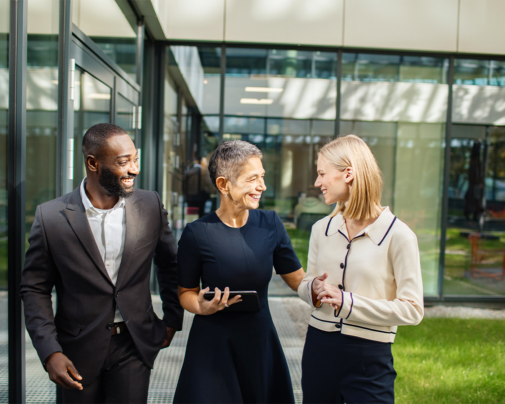 Drei Mitarbeitende stehen zusammen und lachen