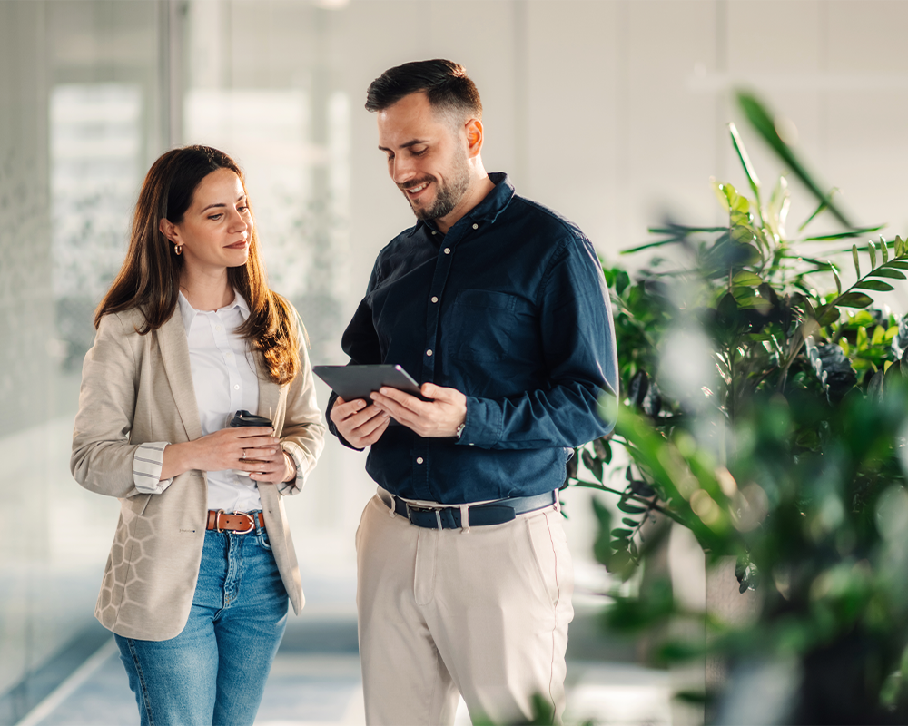 Geschäftsfrau und Geschäftsmann blicken auf ein Tablet