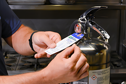 A Pye-Barker Technician examining a Fire Extinquisher