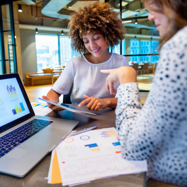 Colleagues discussing finance charts and graphs on a laptop