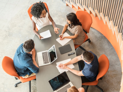 Group of young workers sitting around oval table