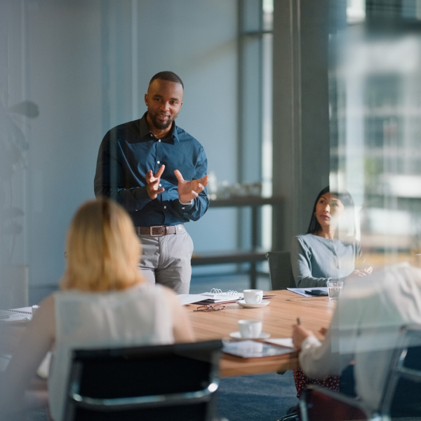 Man standing talking to team at table