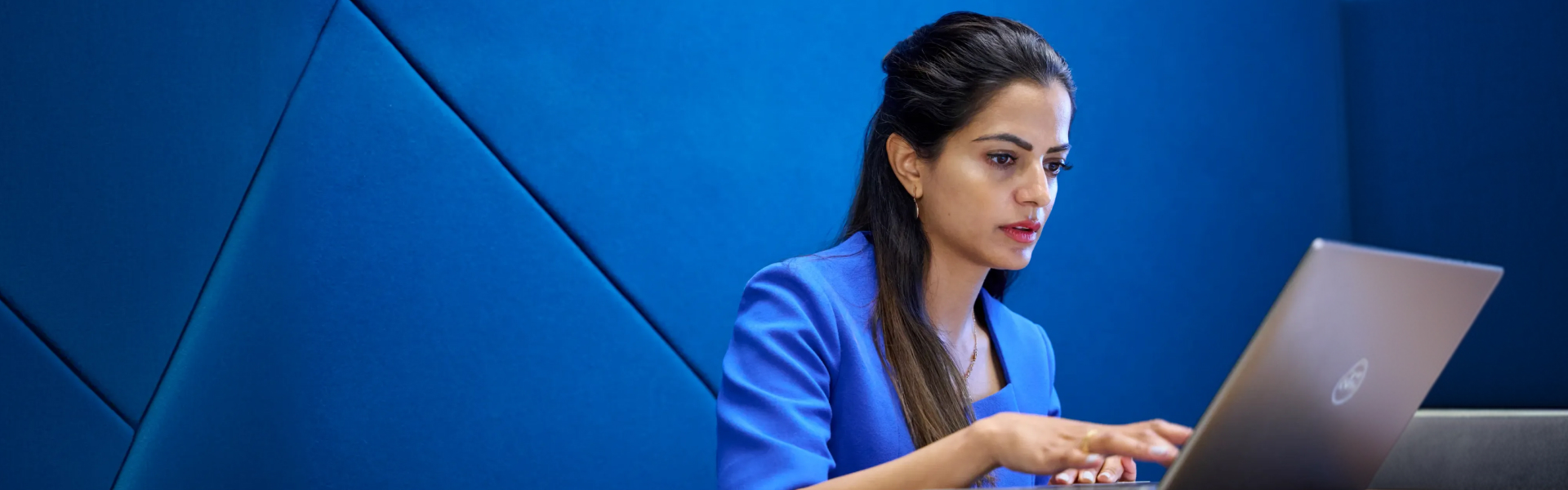 Serious woman at laptop with blue background