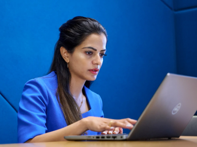 Serious woman at laptop with blue background