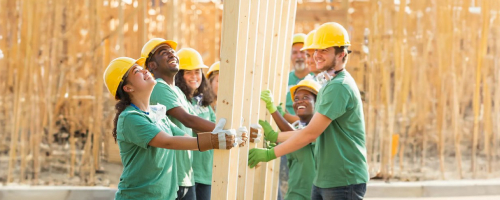 Team in green shirts lifting a wooden frame