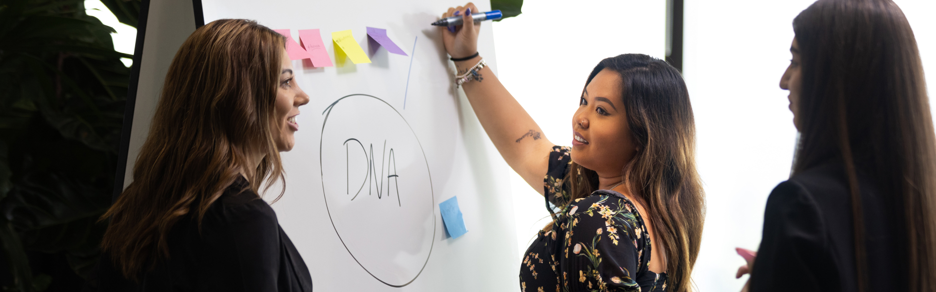 Three women around a whiteboard with DNA on it