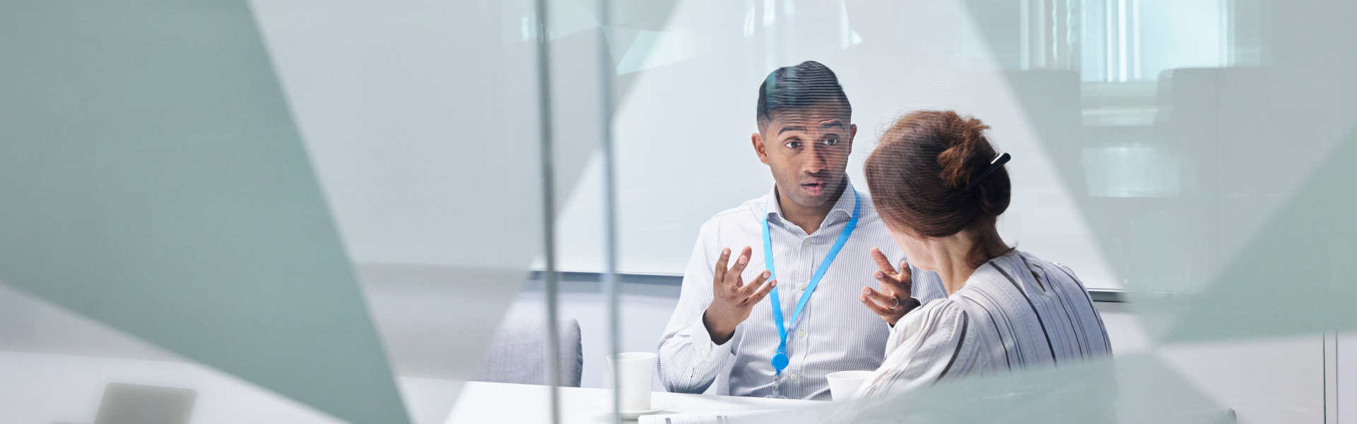Two employees in a meeting room behind glass wall