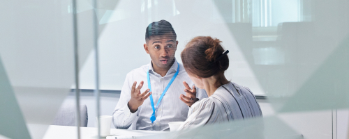 Two employees in a meeting room behind glass wall