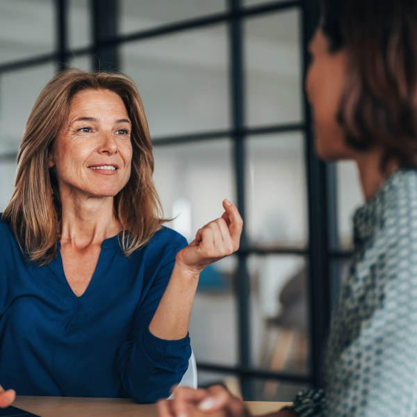 Two women having a focused and friendly conversation at a desk