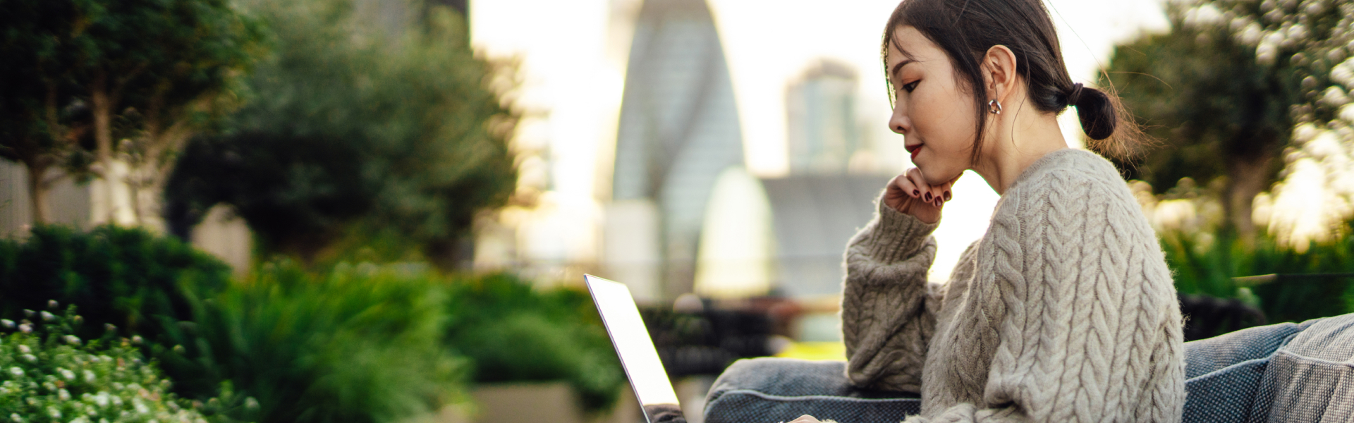 Young Asian woman working on laptop outdoors