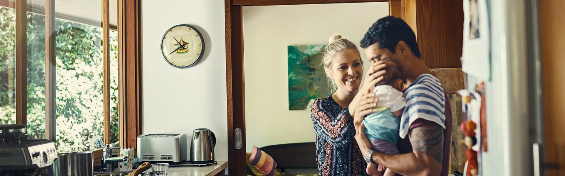 Young couple in kitchen with man holding a baby