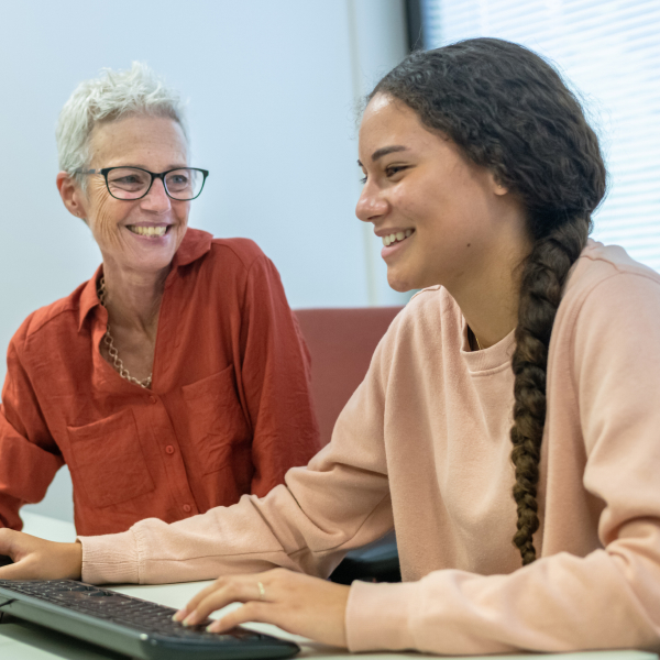 Young woman being mentored by older lady at computer