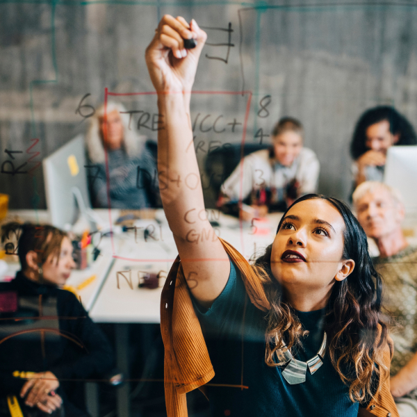 Young woman stretching to write on a window in meeting room