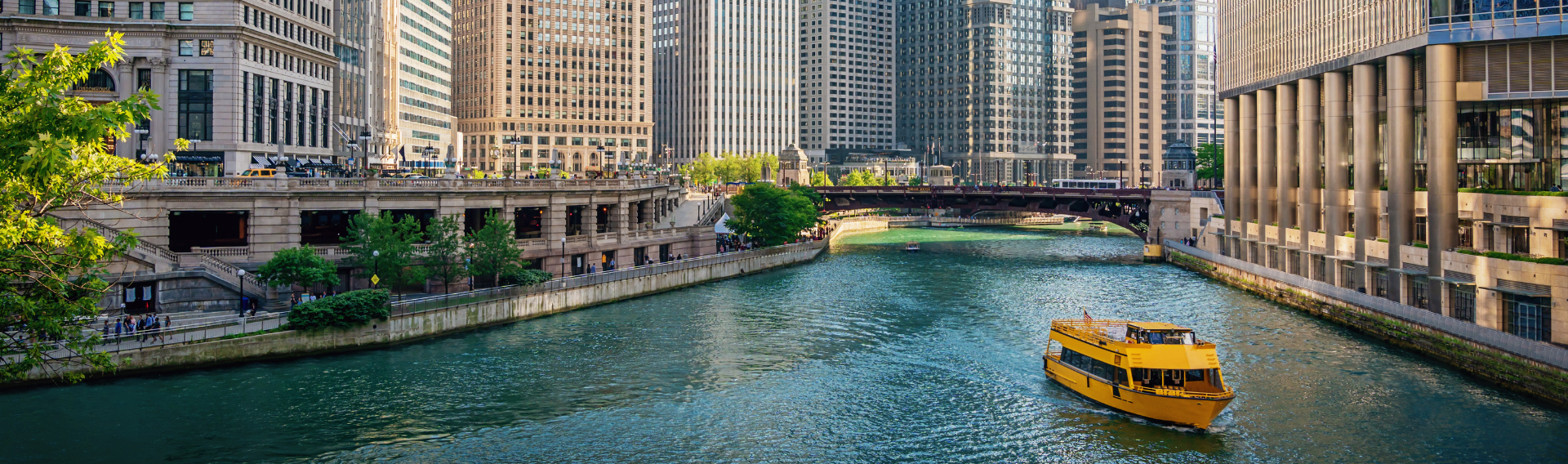 View of the Chicago River surrounded by modern high-rise buildings, with a yellow water taxi cruising through the city—highlighting Chicago’s vibrant downtown and architectural appeal.