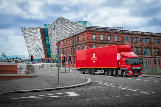 Royal mail lorry driving past large building