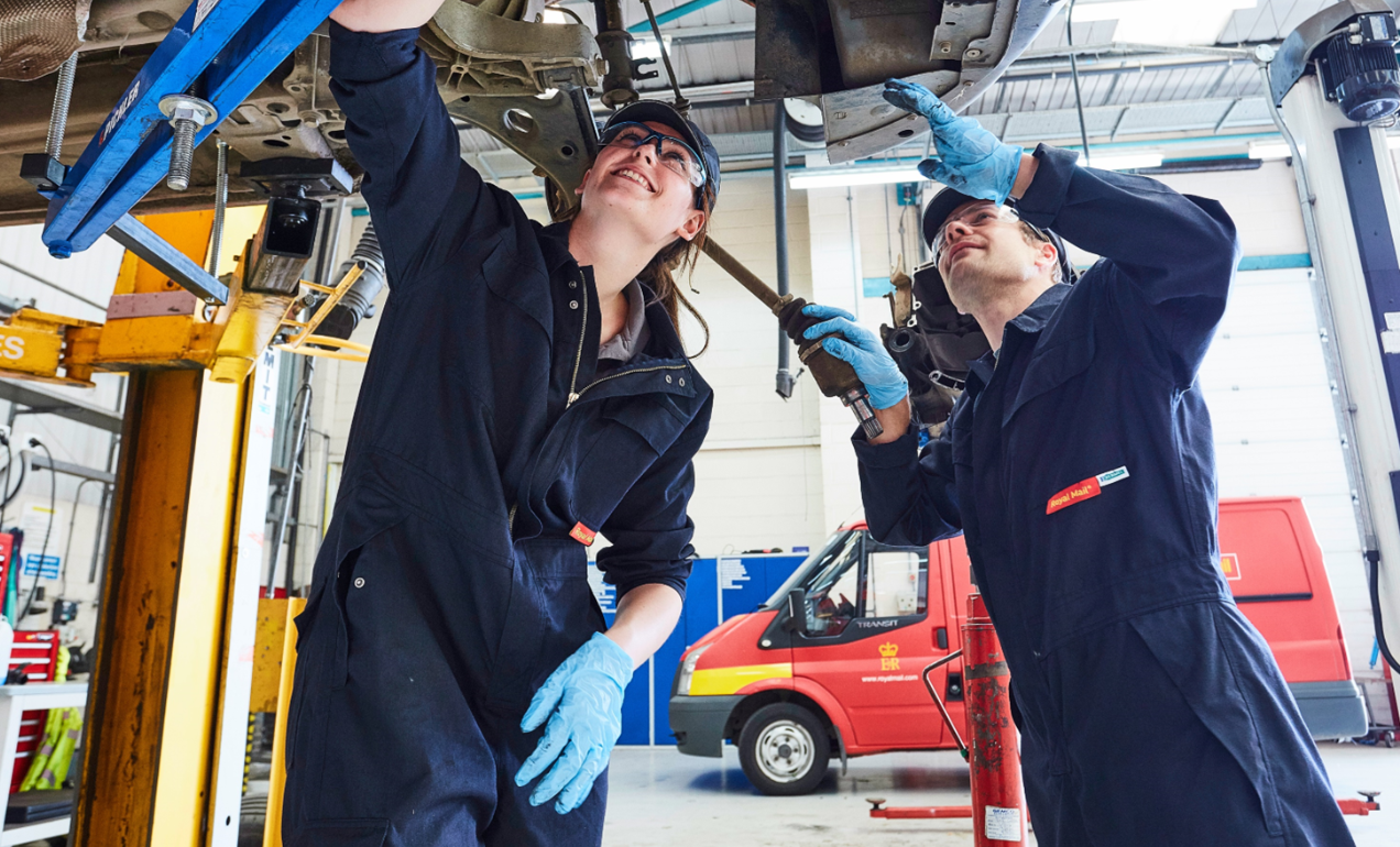 two mechanics working under a raised vehicle