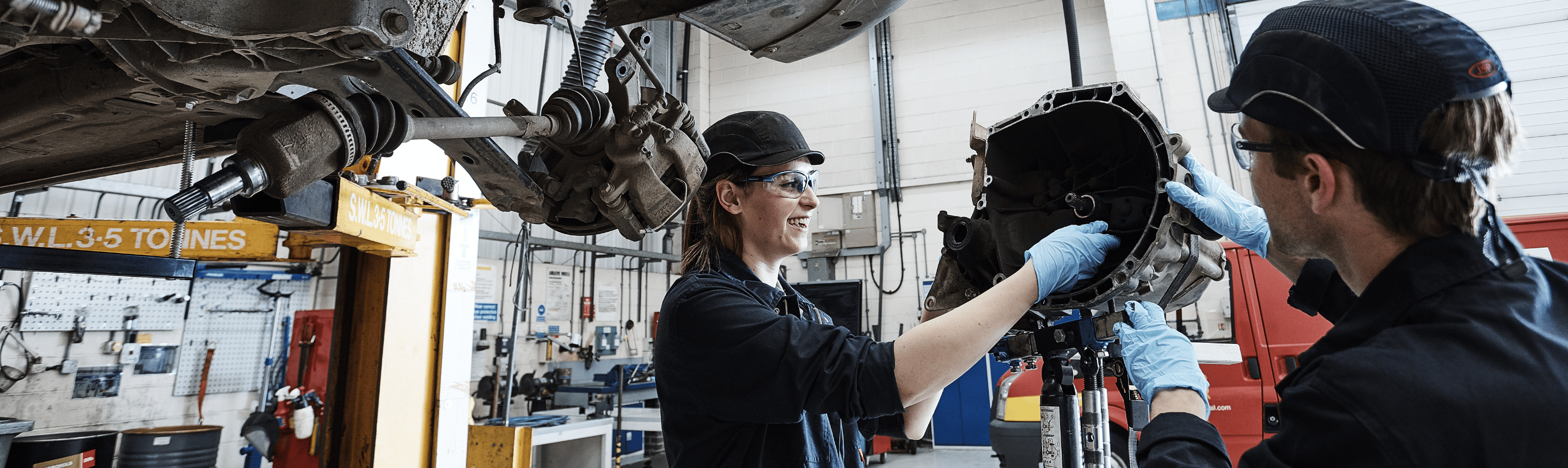 Two mechanics working on a vehicle part