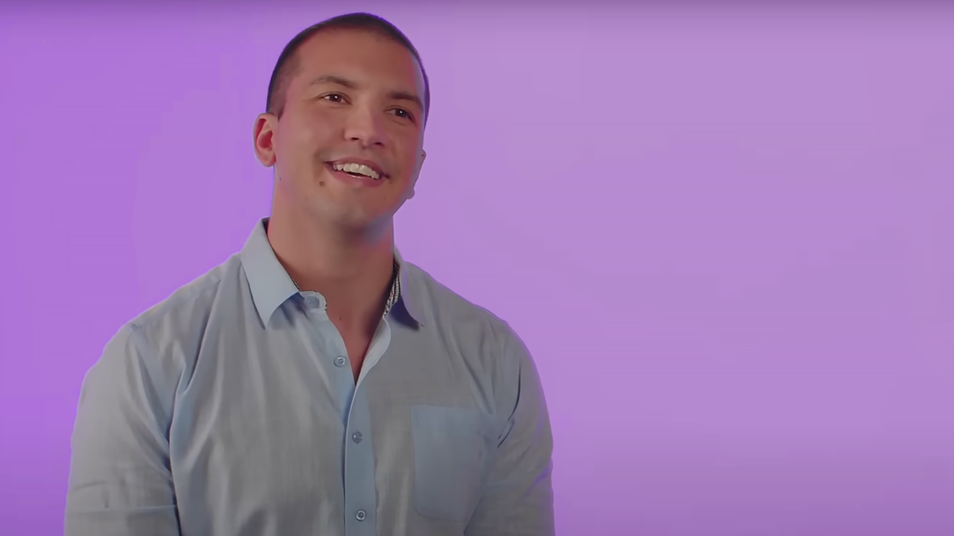 Professionally dressed man talking to camera smiling with a purple background