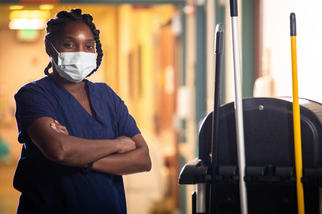 Smiling healthcare professional with mask and cleaning cart