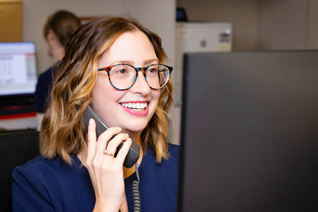 Woman on the phone looking at computer and smiling