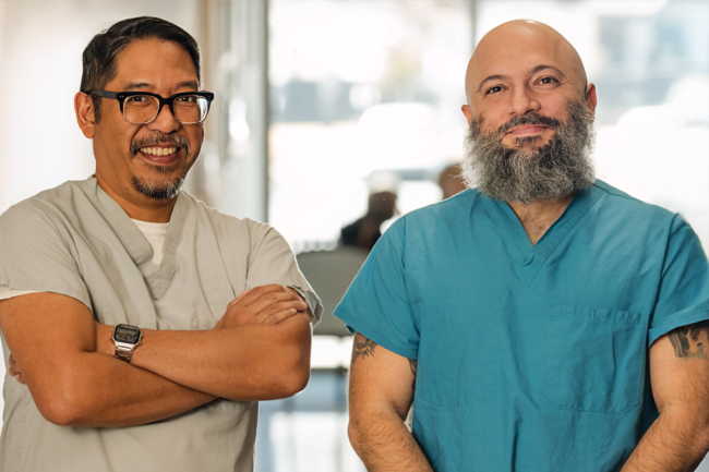 Man with glasses arms crossed man with a beard smiling