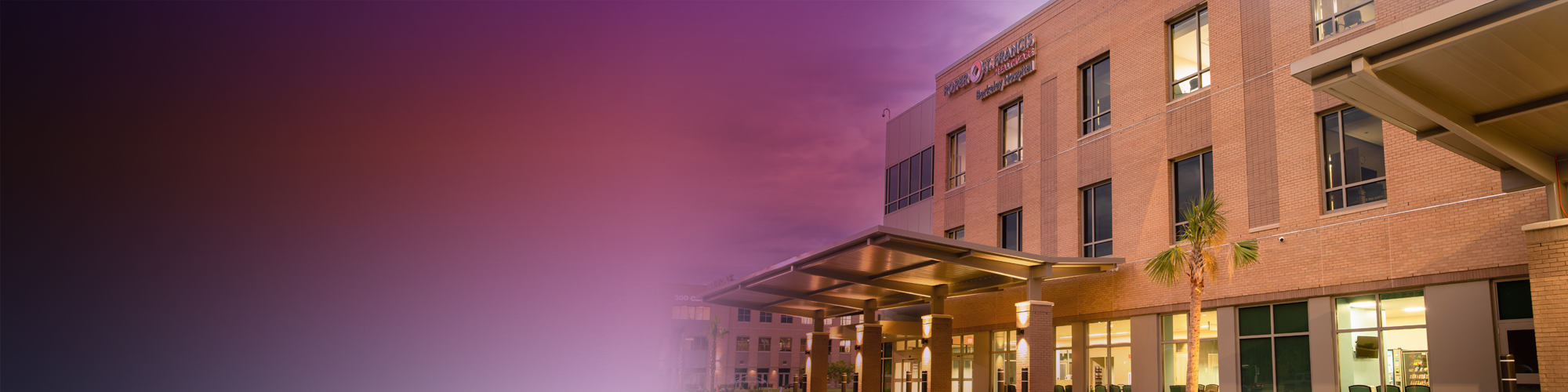 Exterior view of a tan building with lots of windows with a blurred gradient background transitioning from dark to light tones