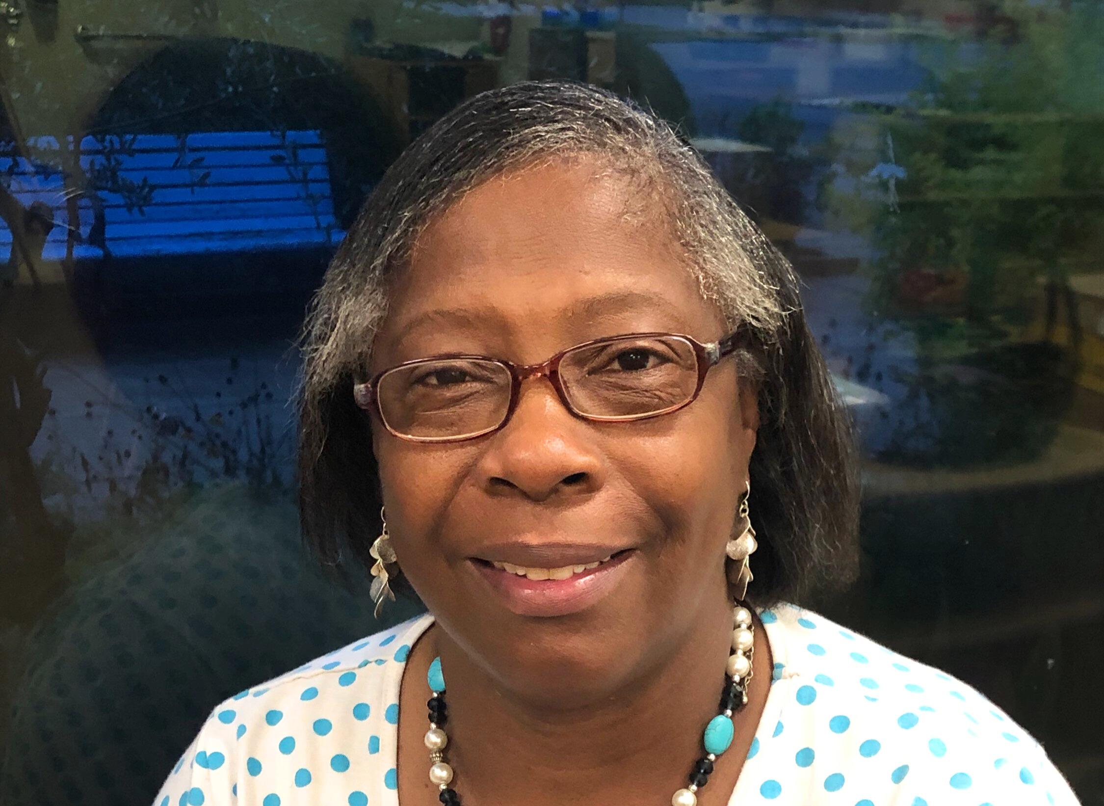 Woman with glasses smiling wearing a polka dot shirt