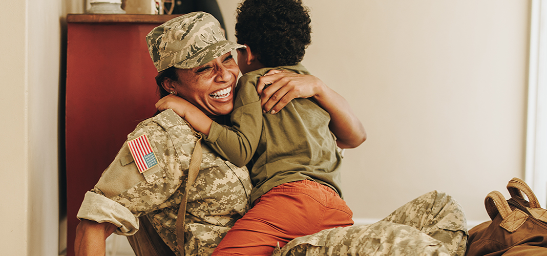 Military woman and young boy hugging in a home