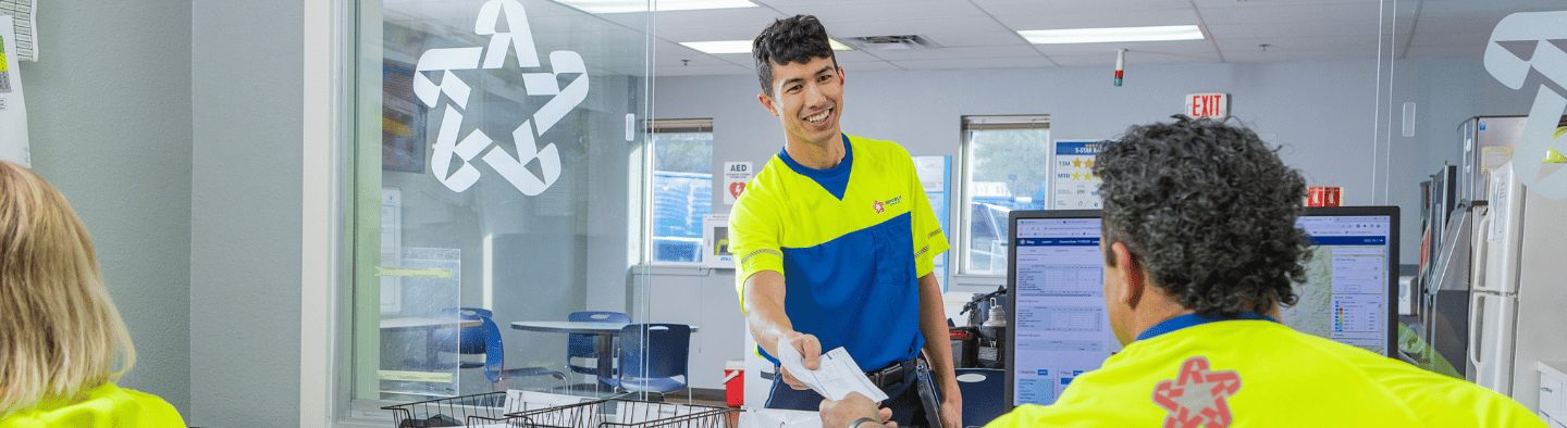 two-employees-smiling-passing-paper