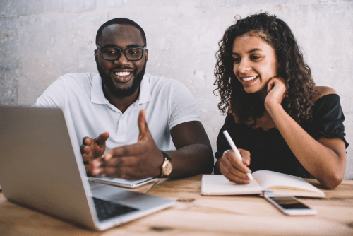 man and woman looking at a laptop screen, woman taking notes