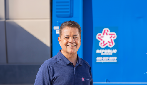 male employee in polo smiling, RS logo in background