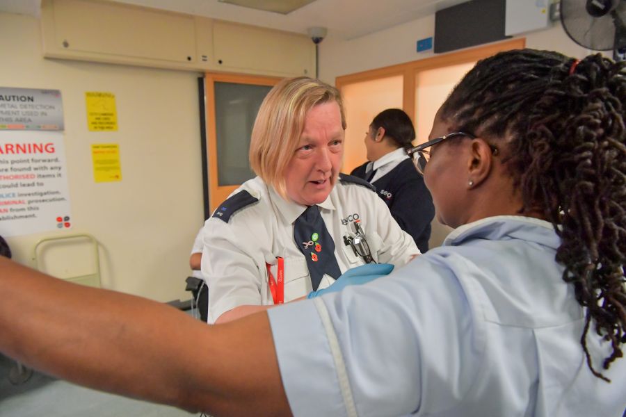 HMP Thameside support officer in a Serco uniform carries out a search on a visitor