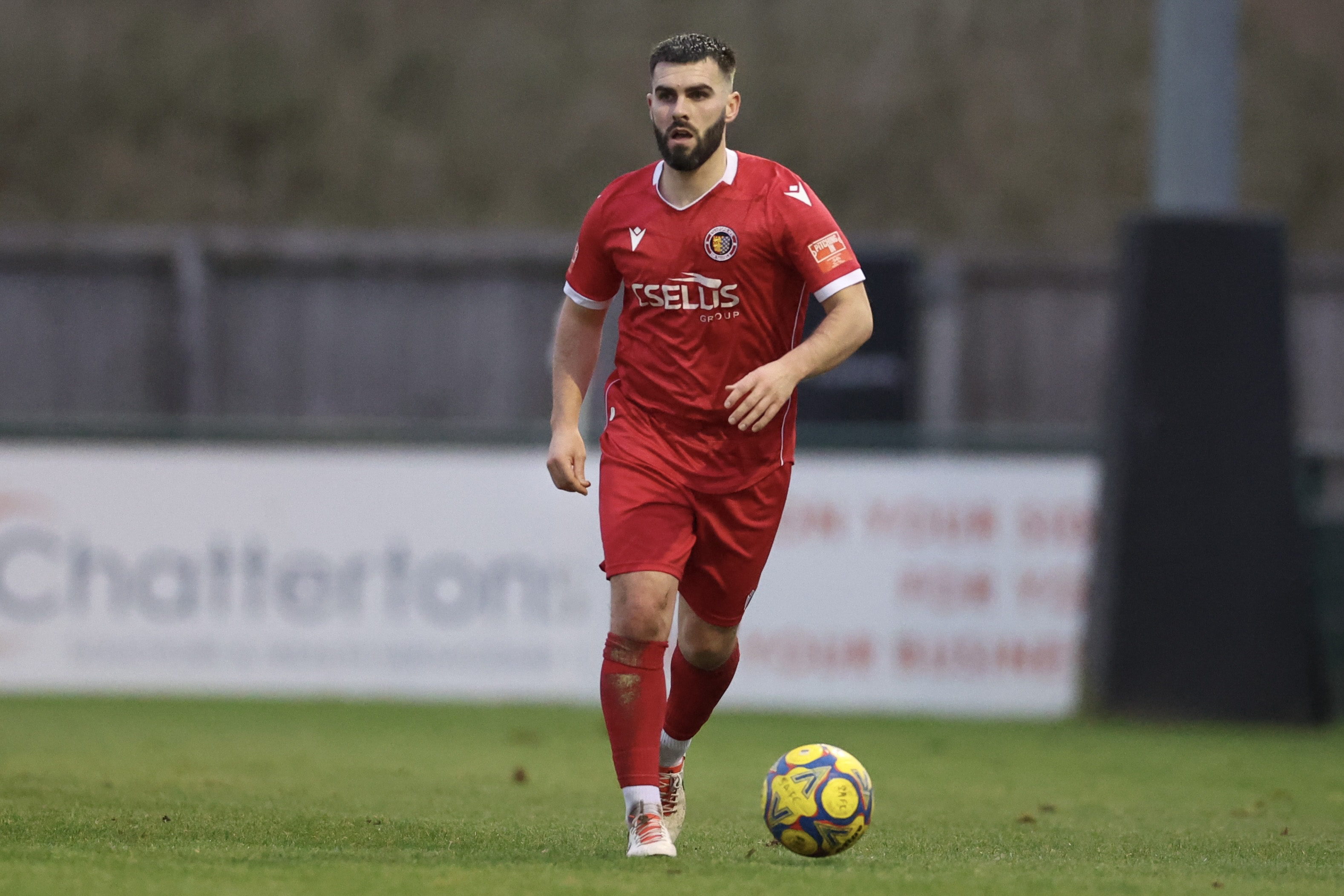 A man in red football clothing and a football.