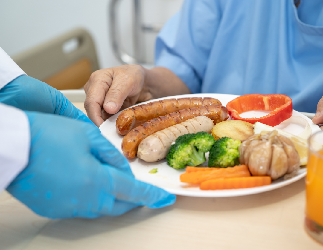 A plate of food being given to a patient in a blue hospital gown