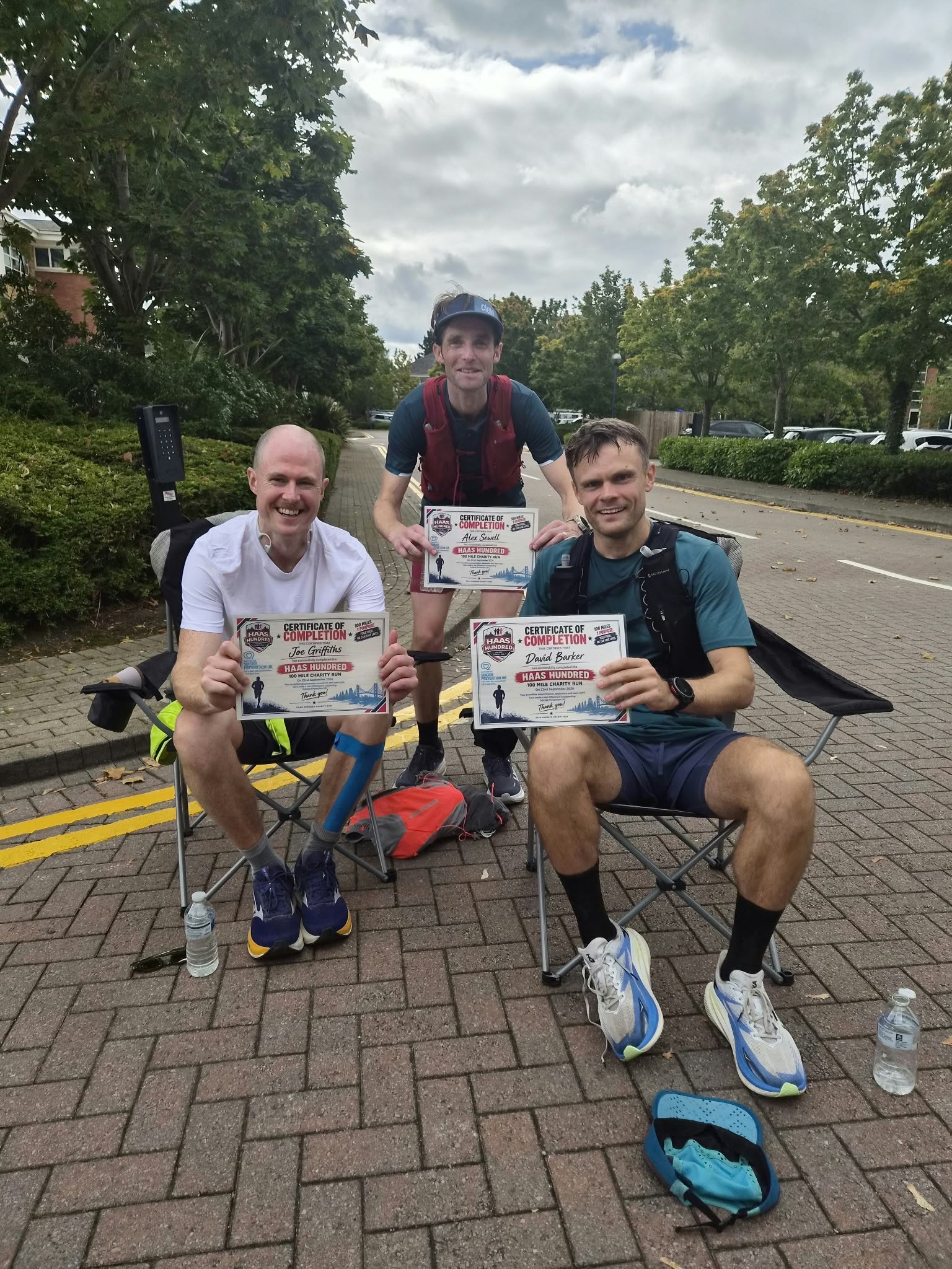 Photo of three men on camping chairs holding up certifications of completion