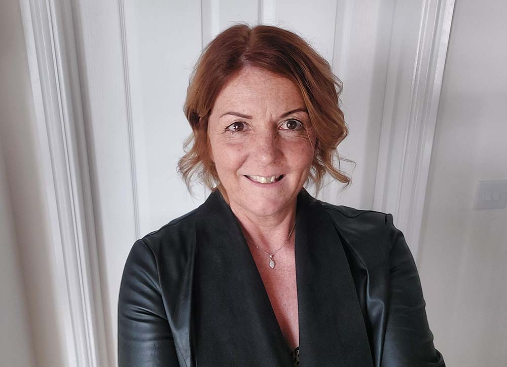 A woman in a black jacket, smiling at the camera