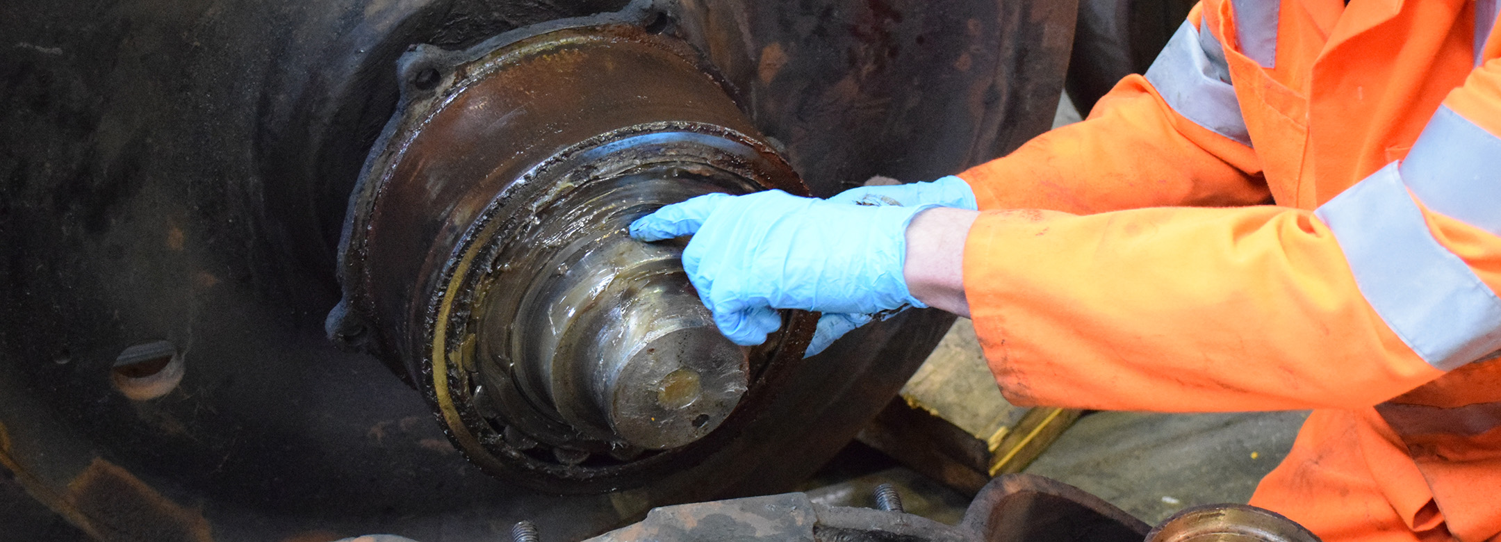 A train wheel and person pointing in blue latex gloves
