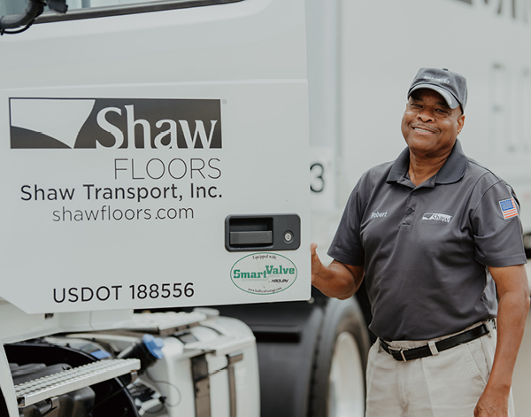 Shaw transportation assocaite driving a truck outside of a plant.