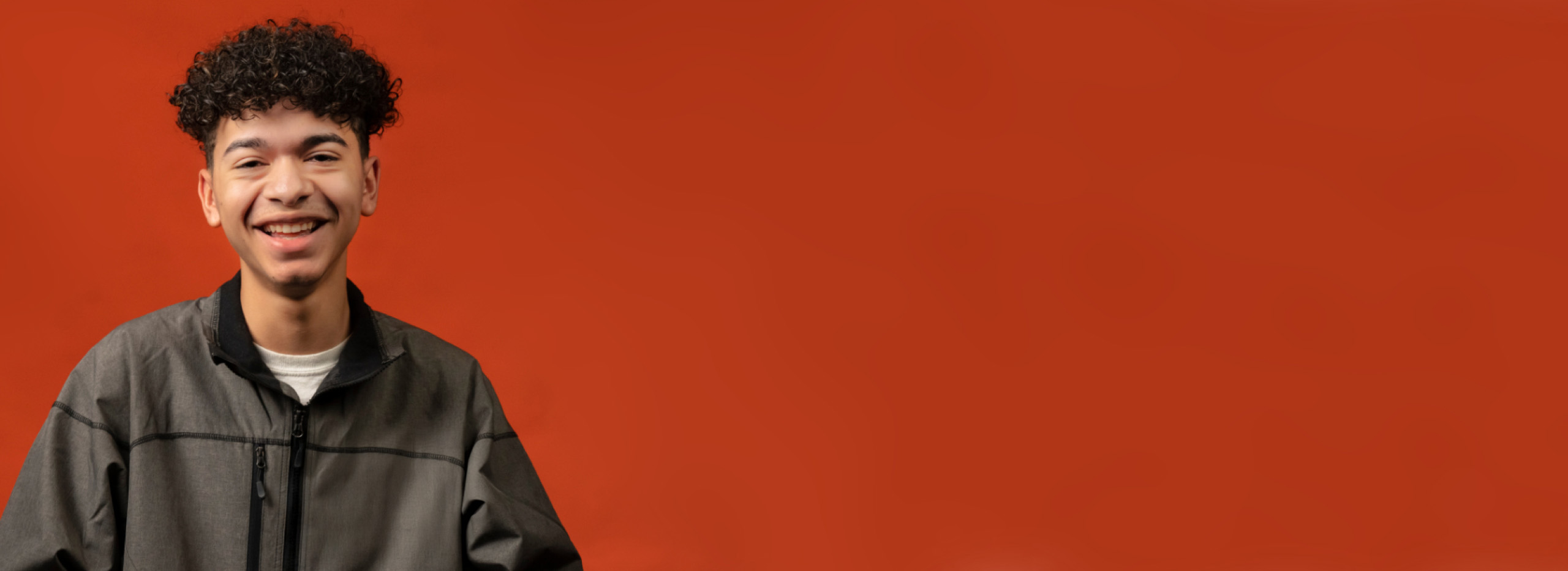 Orange backdrop with a smiling college intern.
