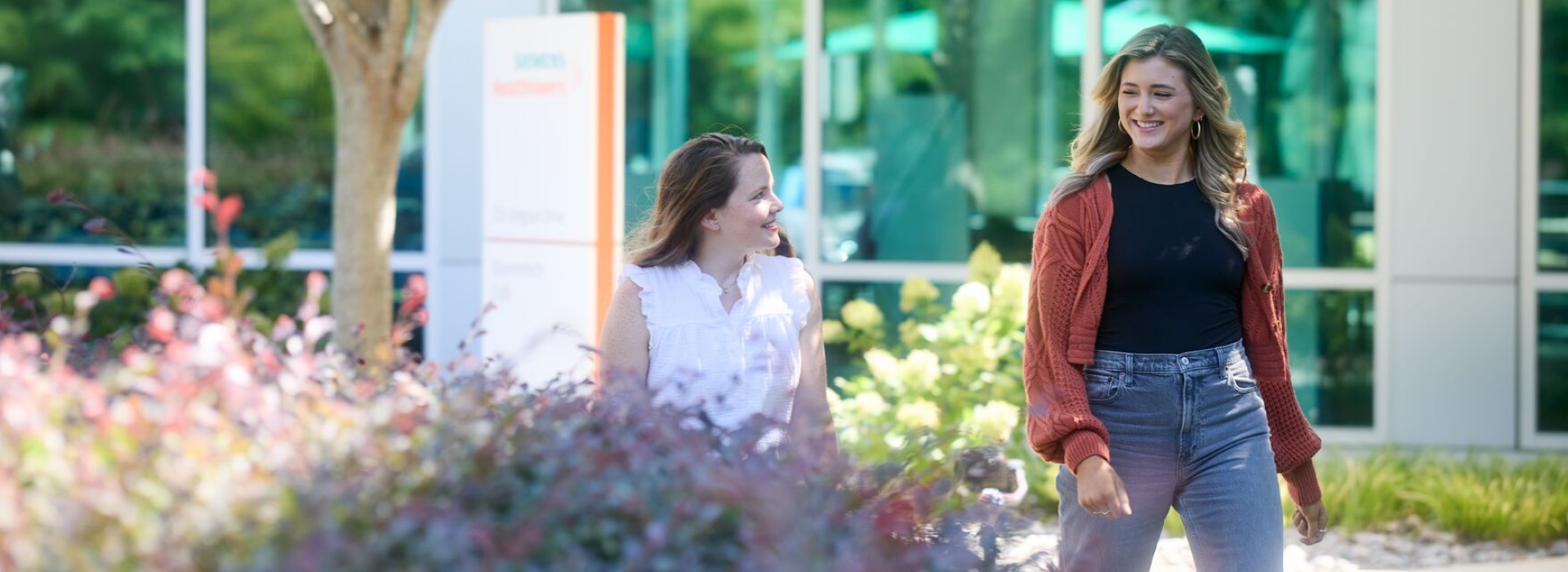 Two female Healthineers walking and chatting outside a Siemens Healthineers building